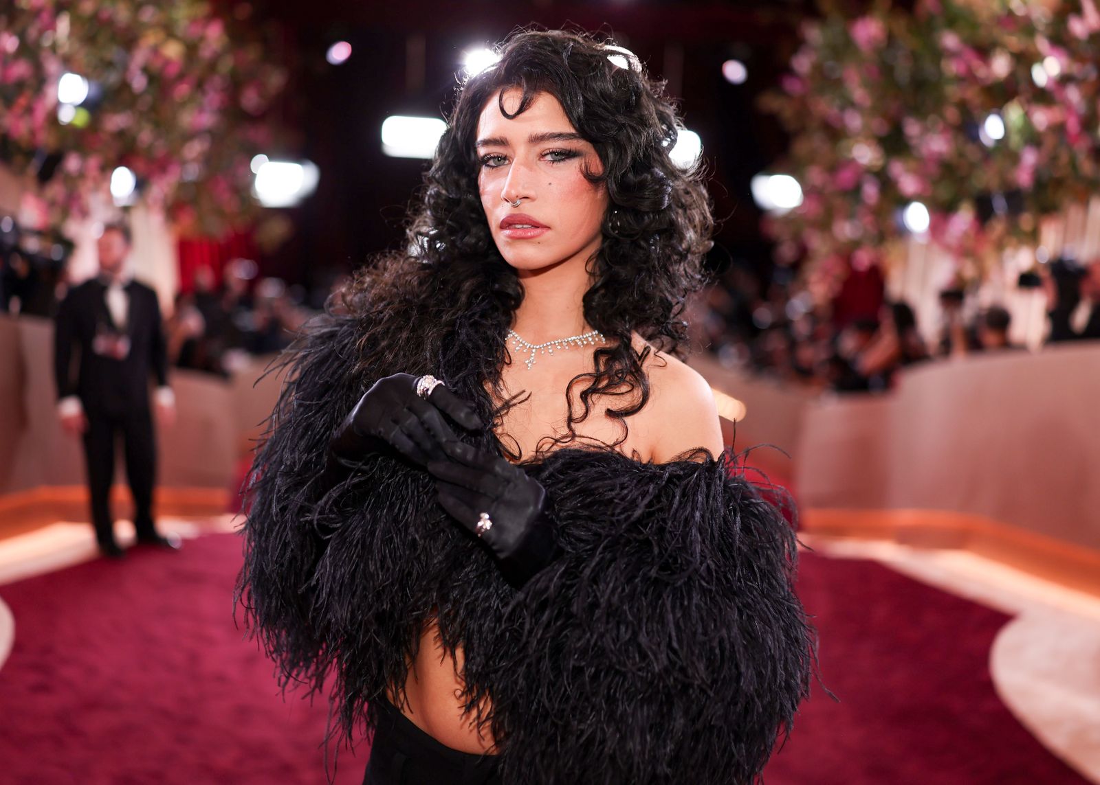 Image may contain black hair, hair, adult clothing, gloves, face, head and fashion