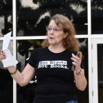 A woman wears a T-shirt that says "Ban bigots not books" Address the crowd.