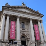 Column-shaped building facade, hung with pink banners.