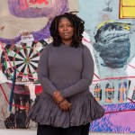 A black woman stands in front of a large painting.