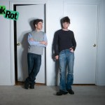 Danny Cole (left) and Anthony Poe stand against a white wall with two doors.