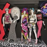 Five wigged white mannequins wear chaotic maximalist outfits, emblazoned with Keit Haring's artwork. There are also bases and cutouts by Keith Haring, both featuring blocky creatures with rough black outlines.