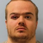 A man with dark eyes looks into the camera.