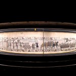 A long tapestry lined with various figures, horses and ships.