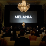 First lady Melania Trump greeted visitors under a giant chandelier at the White House, her name written on a screen behind her.