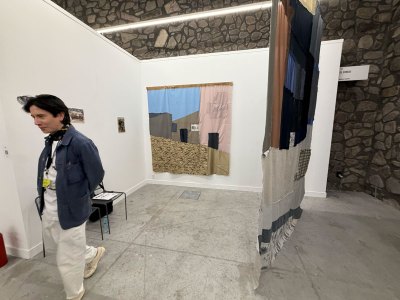 A man walks among fabric paintings depicting buildings.