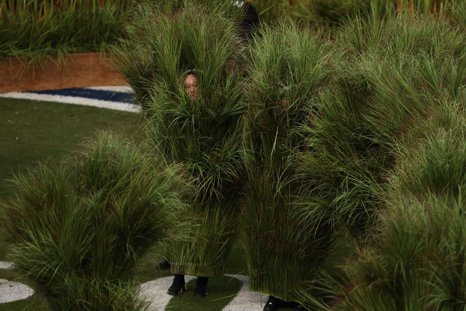 Image may contain plants, grass, people covering, hiding adult clothing, footwear and shoes