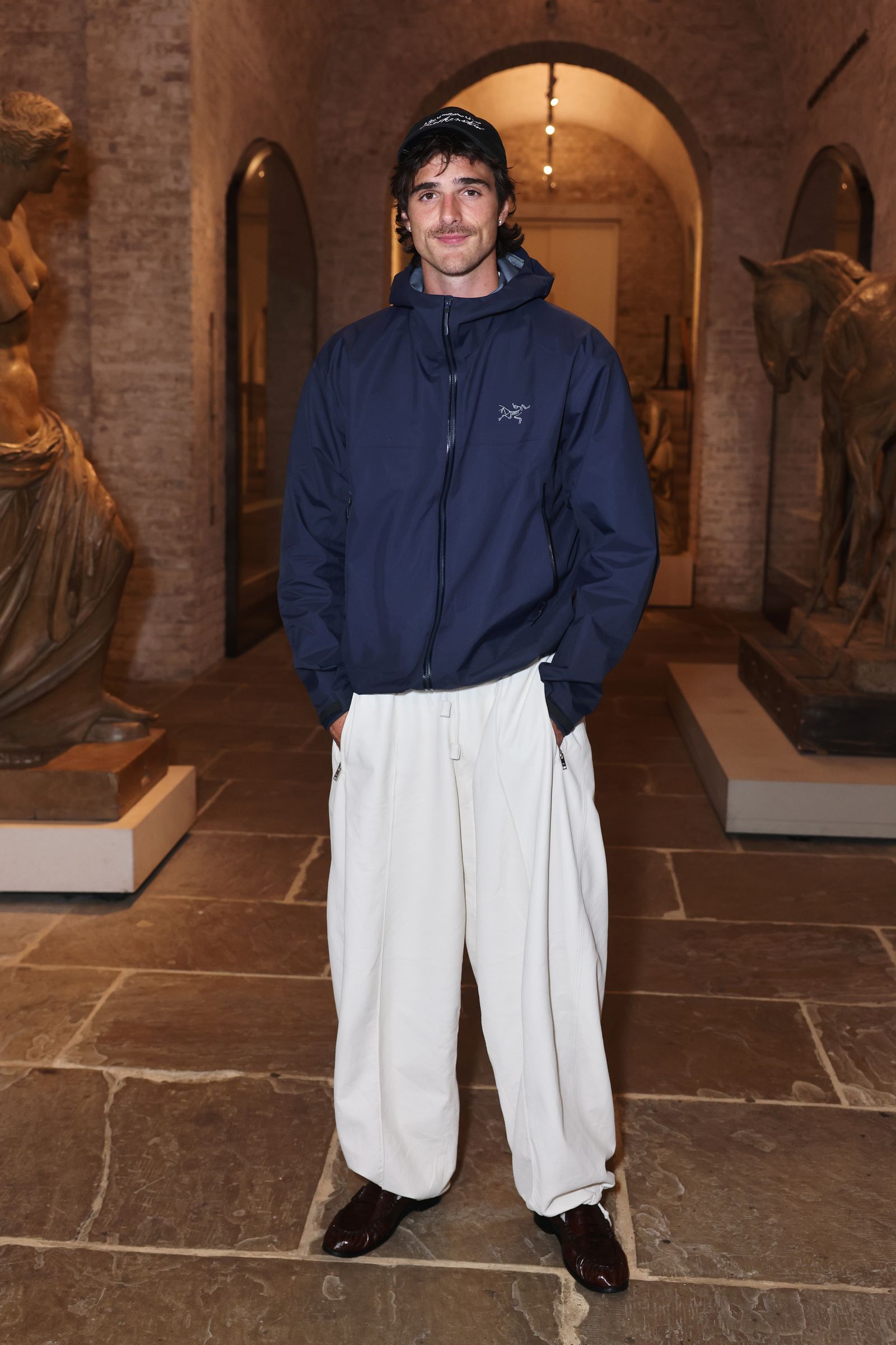 Image may feature a person standing, clothing, coat, adult hoodie, knitwear, sweater, sweatshirt, face and head