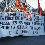 A group of protesters held signs in front of the glass pyramid.