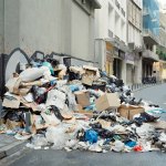 Color photo of a large pile of garbage on a narrow street.