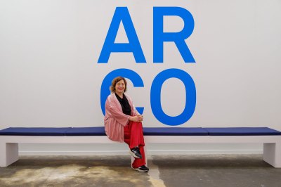 Maribel López sits on the bench in front of the blue ARCO sign.