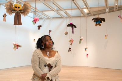 A man stares at an installation of stuffed animals and dolls suspended from nooses.