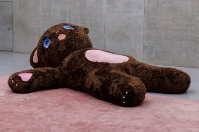 A giant stuffed animal sculpture with sharp teeth and a pink belly.