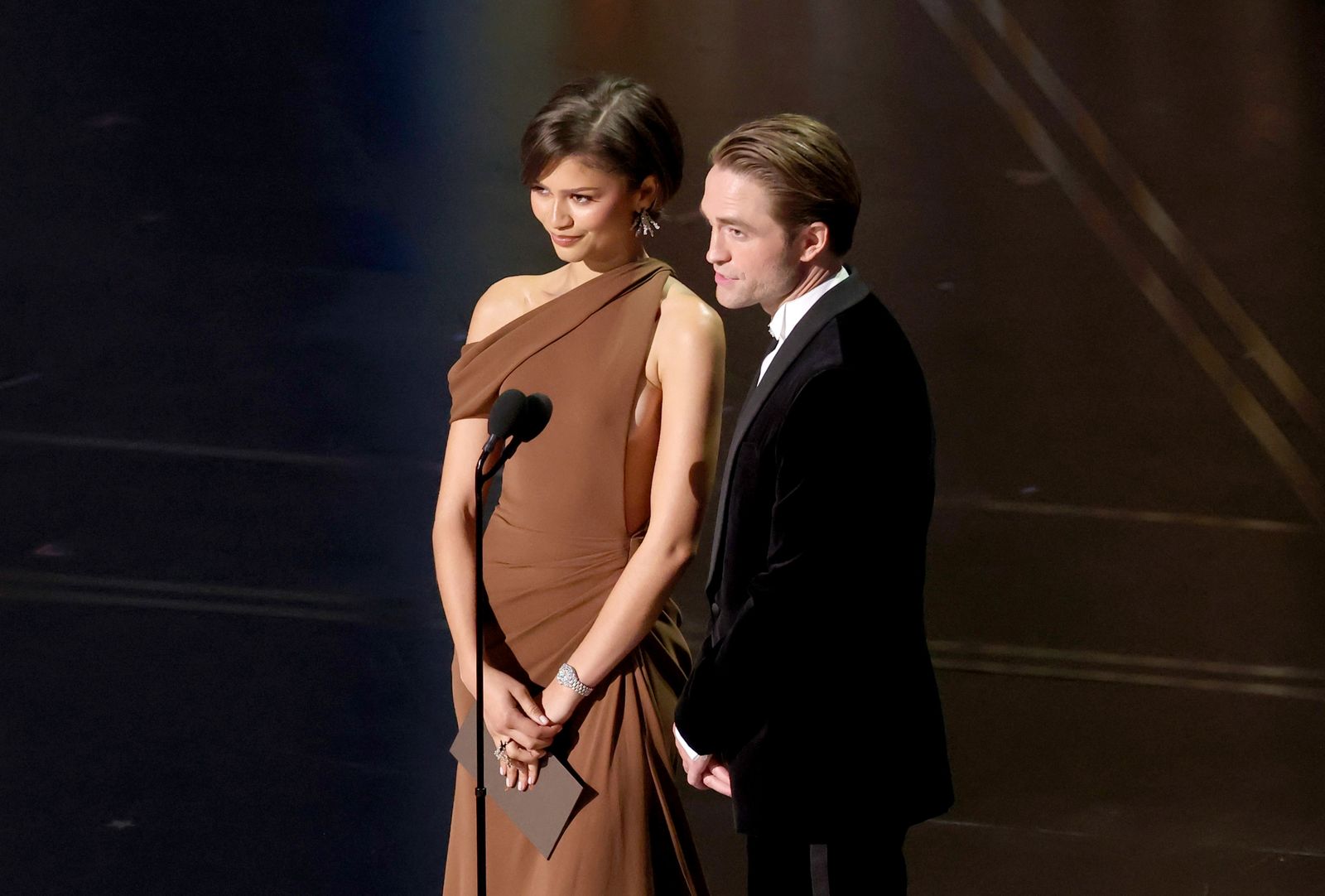 Image may contain Robert Pattinson Zendaya adult body parts, hands, formal attire, clothing, dress and head