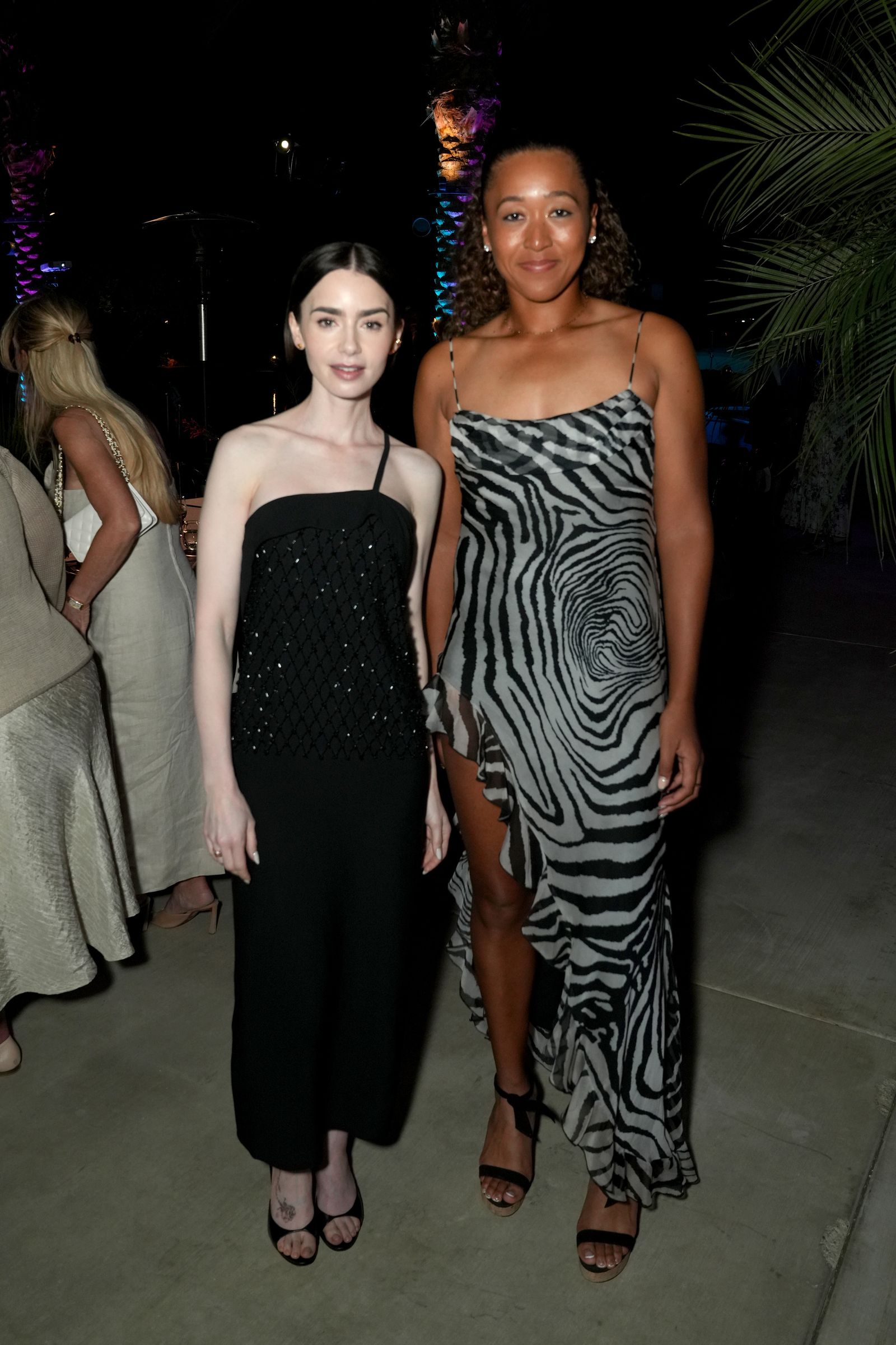 Image may contain Naomi Osaka Lily Collins People Photobombing Clothes Dresses Adult Urban Wedding and Evening Dresses