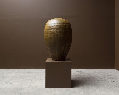 A large brown container on a brown base in a brown painted gallery. 