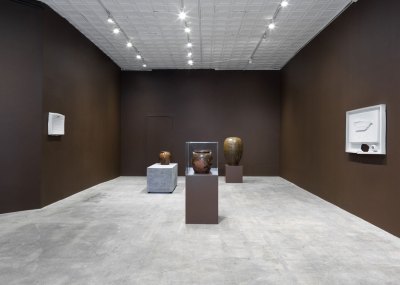 View of a gallery exhibition with ships in the middle gallery and two artworks hanging on the opposite wall.