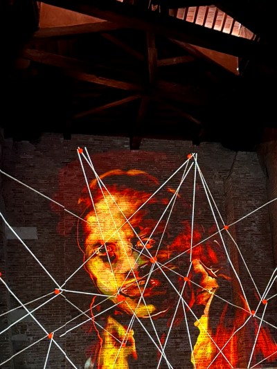 A person's face is projected onto the bricks with white lines on them.