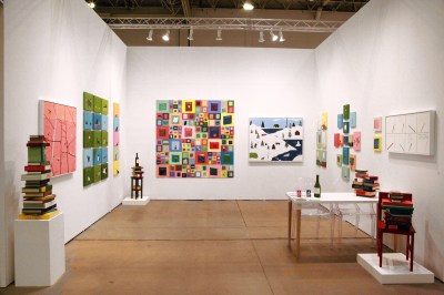 Photo shows an art fair stall filled with piles of paintings, calligraphy and sculptures