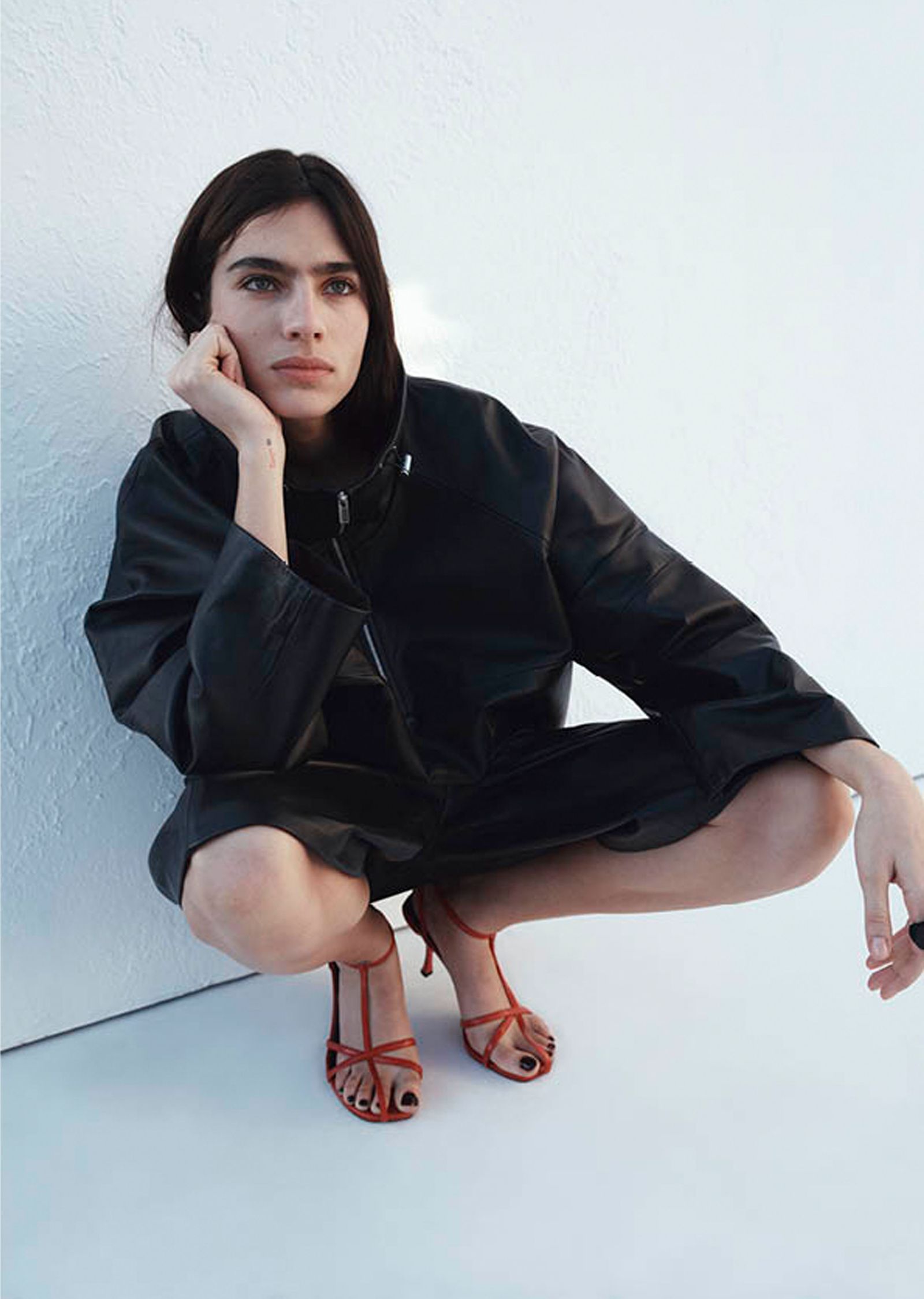 The image may include a person sitting, clothing, coat, adult footwear, sandals, high heels, toe box and face