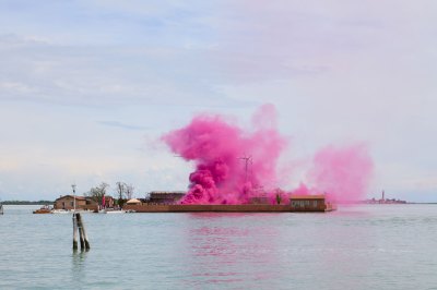 A cloud of pink smoke rises on an island in the Venetian lagoon.