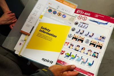 A man opens a folder containing various pamphlets promoting aircraft safety information.