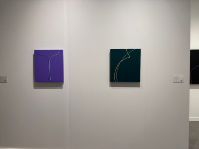 Two abstract paintings hang on the walls of the fair booth.