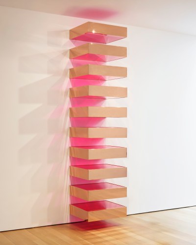 The sculpture hanging on the wall consists of ten rectangles with a light brown metal exterior and red glass top and bottom
