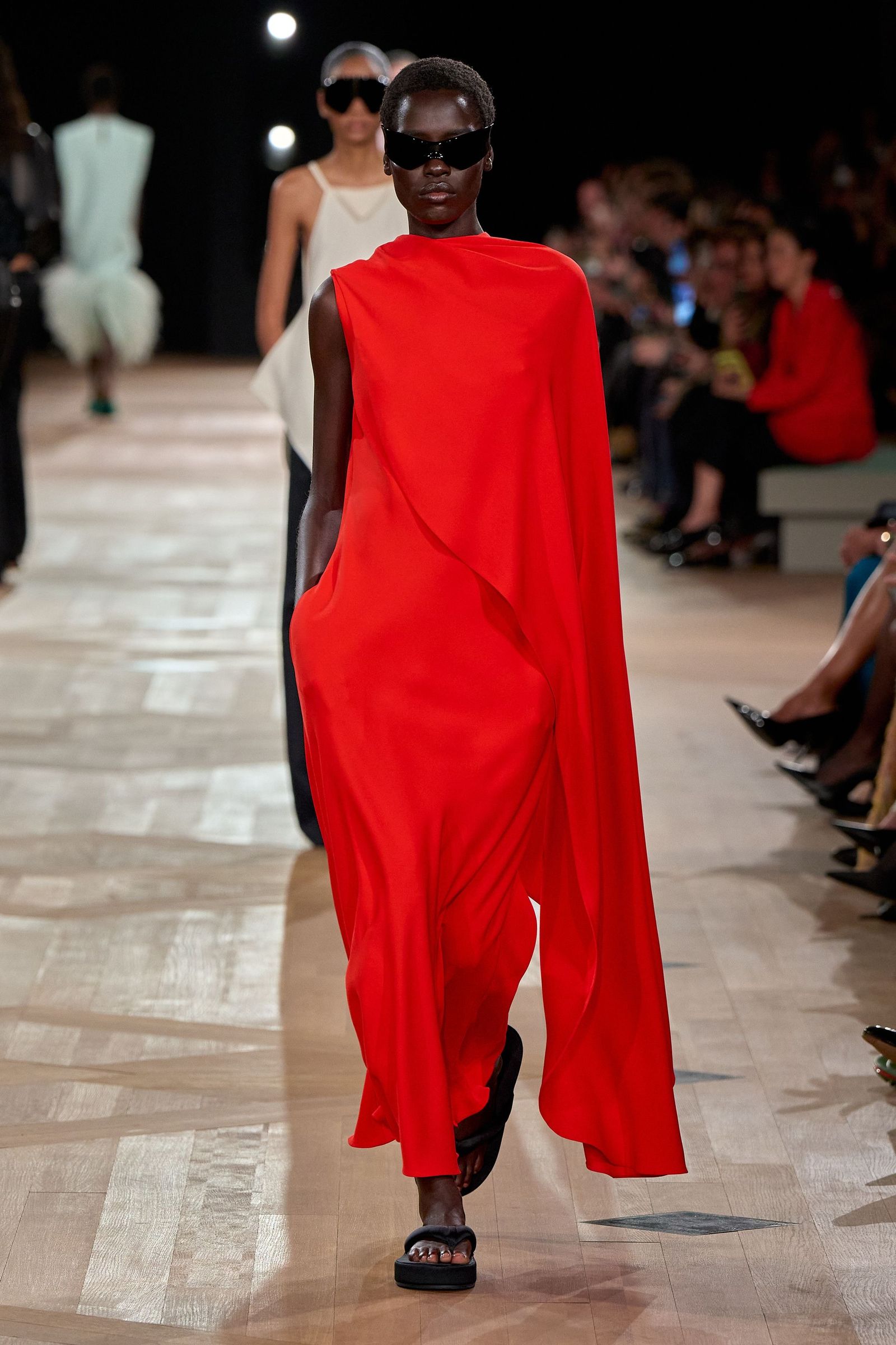 Image may contain Florence Kasumba fashion adult accessories glasses walking cape clothing dress and face