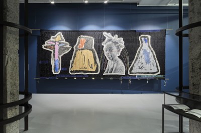 A large textile showing a black girl between three shapes resembling painted vessels.