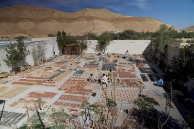 A group of workers create a mosaic in a hollow in the desert.