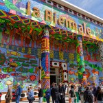 A group of people walked in front of a colorful column-shaped building with the words 