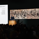 An auctioneer at Christie's stands on a podium with his fist raised, selling a work by Jackson Pollock "No. 7A, 1948," A large screen behind him displayed an oil and enamel canvas drip painting. The currency board on the left shows the hammer price of $157 million across multiple currencies. The foreground is filled with the silhouettes of a crowded sales room audience.