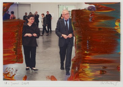 The photo shows artist Gerhard Richter in a suit and art dealer Marian Goodman in a black pantsuit in an art gallery. Parts of the surface are painted with thick areas of abstract color
