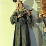 The photo shows a 5-foot-tall wooden sculpture of a saint wearing antique robes and holding a cross.