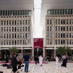 People walking in front of labeled buildings "Art Basel Qatar"
