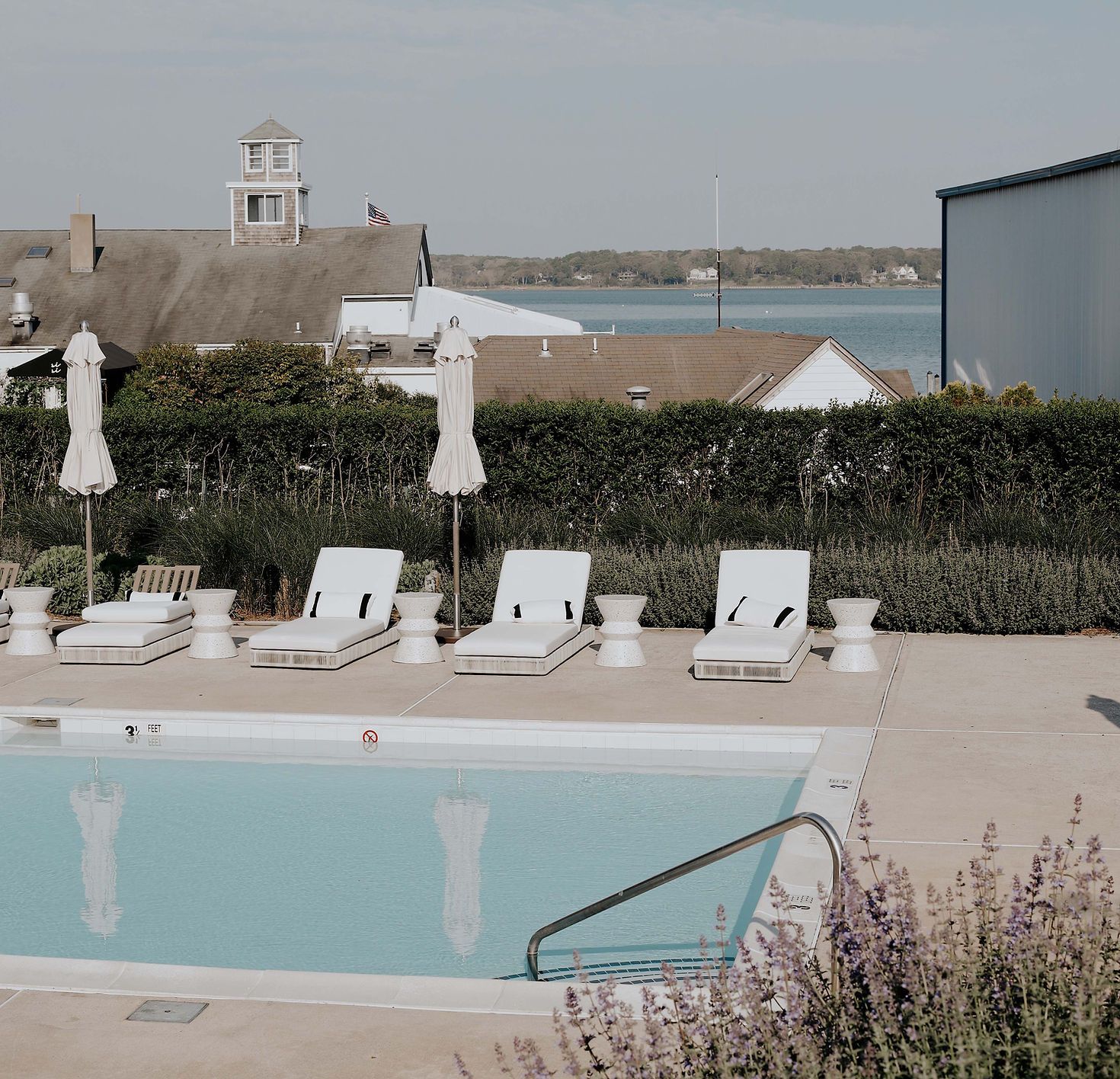 Image may contain pool water, swimming pool, chairs, furniture, flags, outdoor structures, architecture, houses and housing