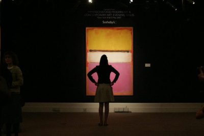An art critic stands in front of a work titled 